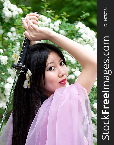 Beutiful japanese woman in pink dress wields a sword