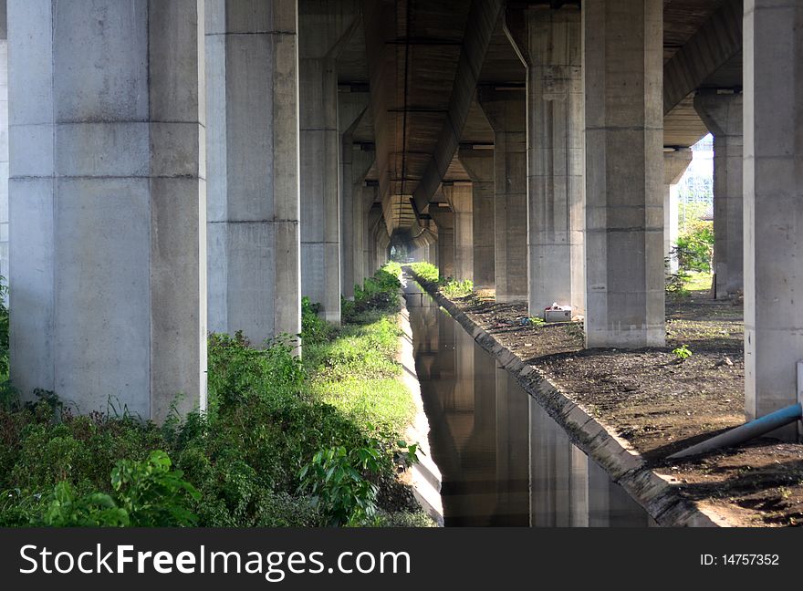 Tunnel under freeway with concrete pillars with sun shining through