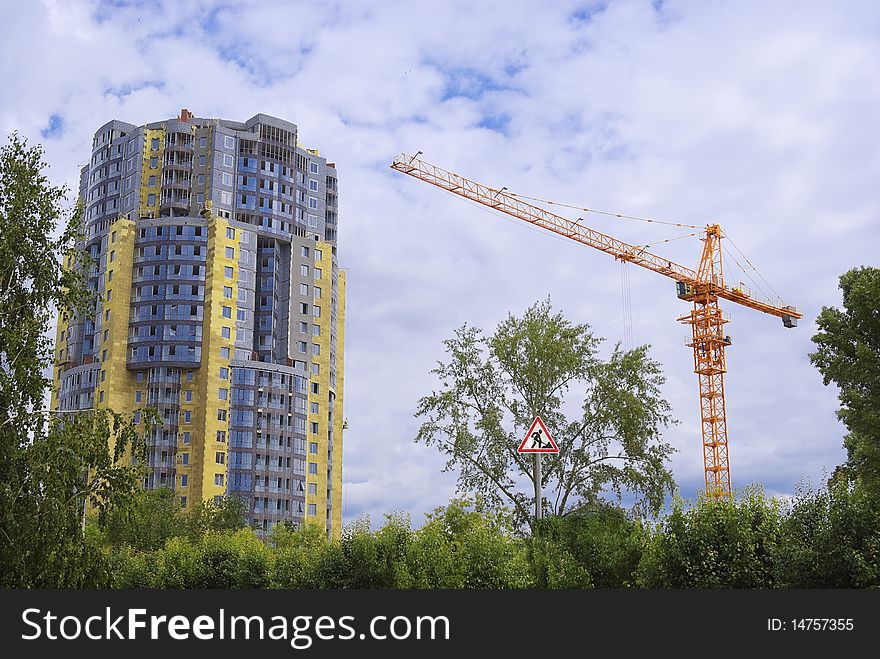 New residential building and the orange crane in a frame of green foliage. In the centre a sign on conducted civil work. All the picture is real, except the sign on metal column. New residential building and the orange crane in a frame of green foliage. In the centre a sign on conducted civil work. All the picture is real, except the sign on metal column