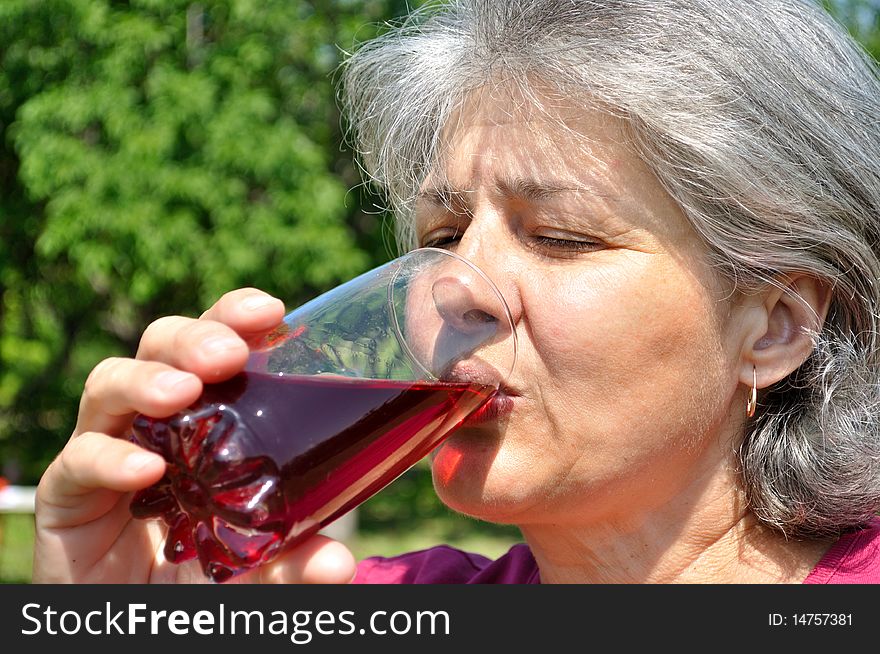 Middle-aged woman with pleasure drinking cherry juice. Middle-aged woman with pleasure drinking cherry juice