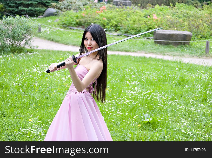 Beutiful japanese woman in pink dress wields a sword