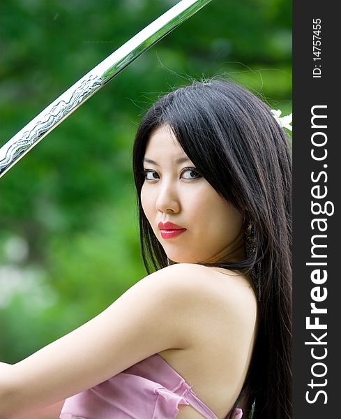 Beutiful japanese woman in pink dress wields a sword