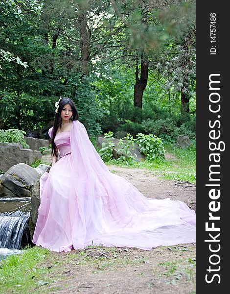 Beautiful Japanese woman in a pink dress sitting on a stone. Beautiful Japanese woman in a pink dress sitting on a stone