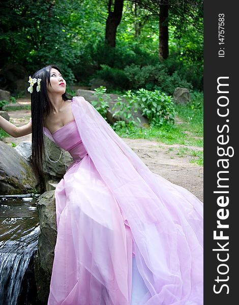 Beautiful Japanese woman in a pink dress sitting on a stone. Beautiful Japanese woman in a pink dress sitting on a stone