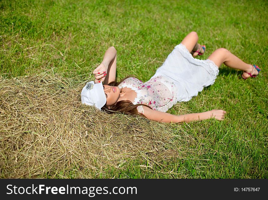 Beautiful girl lying in a meadow near the hay