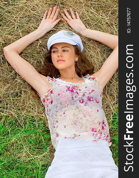 Beautiful girl lying in a meadow near the hay