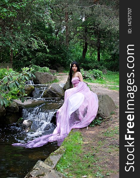 Beautiful Japanese woman in a pink dress sitting on a stone. Beautiful Japanese woman in a pink dress sitting on a stone