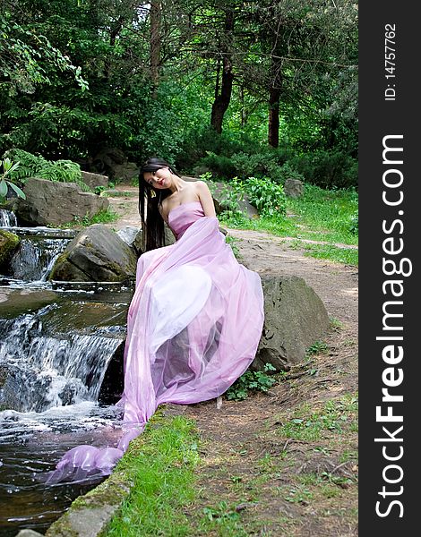 Beautiful Japanese woman in a pink dress sitting on a stone. Beautiful Japanese woman in a pink dress sitting on a stone