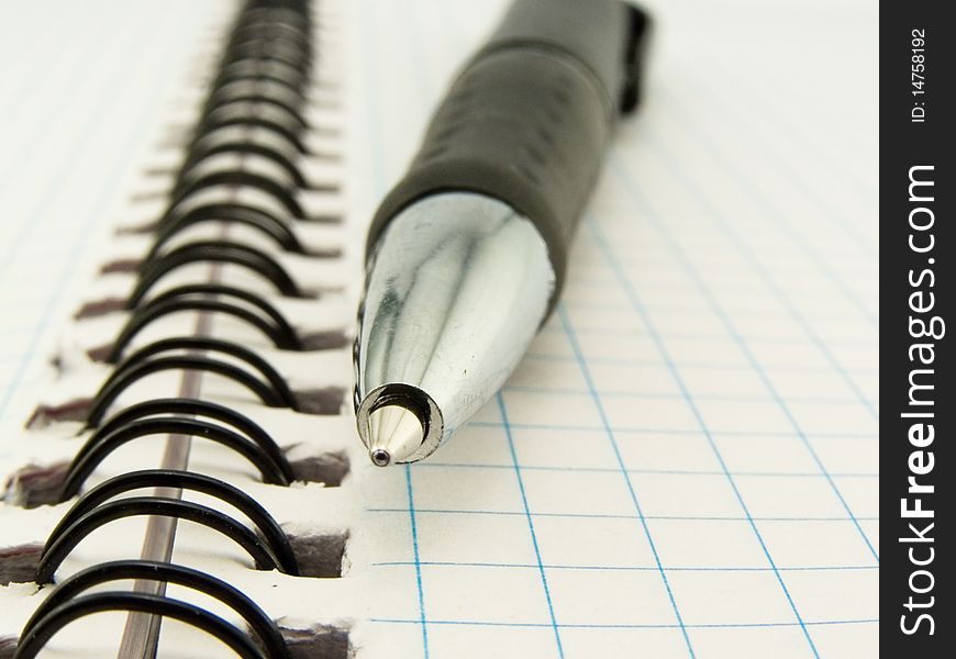 Ball-point pen rests upon clean notebook in check. Ball-point pen rests upon clean notebook in check