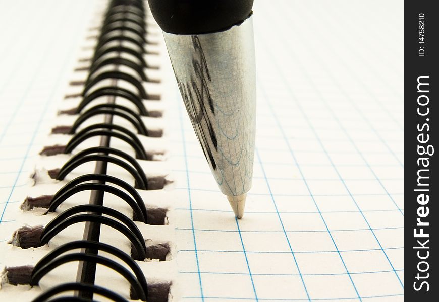 Darkenning ball-point pen on notebook in check which threaded spiraldarkenning ball-point pen on notebook in check which threaded spiral