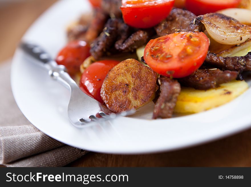 Beef with roasted potatoes,onion and cherry tomatoes; austrian cuisine. Beef with roasted potatoes,onion and cherry tomatoes; austrian cuisine