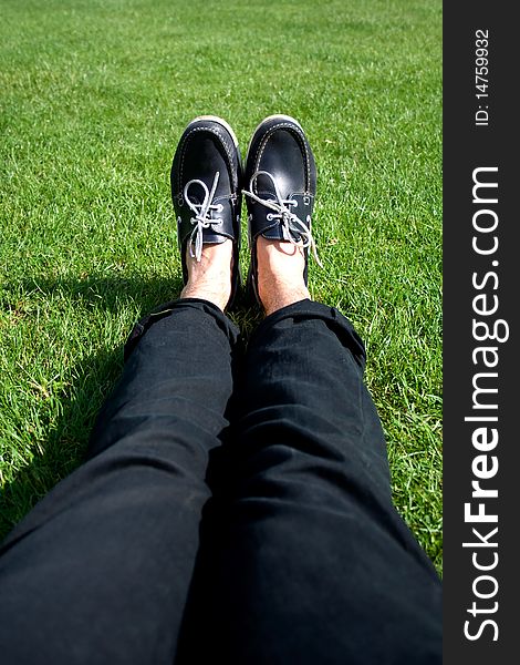 Blue leather shoes at the end of long male legs on a grass background. Blue leather shoes at the end of long male legs on a grass background.