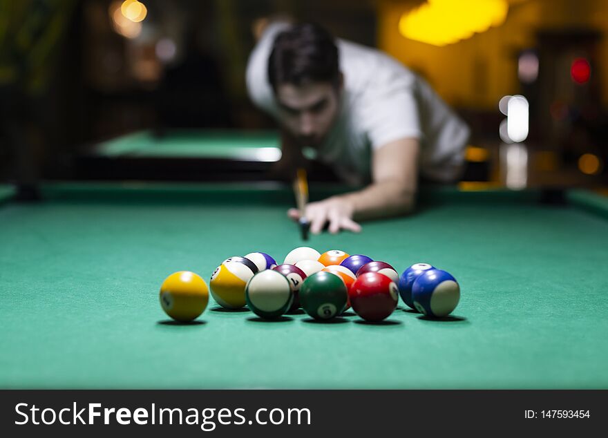 Handsome young man playing pool in pub