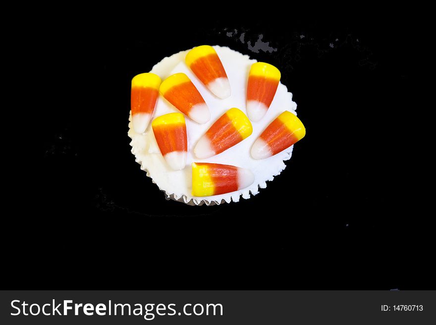 Yummy candy corn decorated cupcake on a black background. Yummy candy corn decorated cupcake on a black background