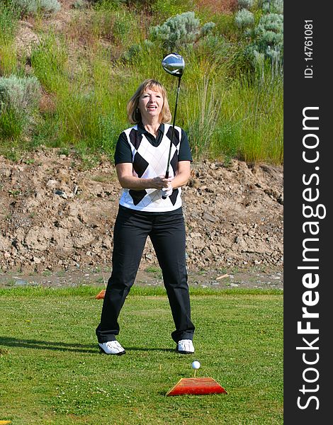 Blond female golfer on the tee-box with a driver