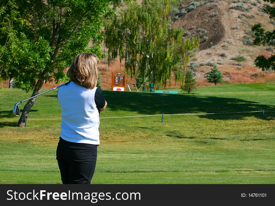 Blond female golfer following her ball after a shot