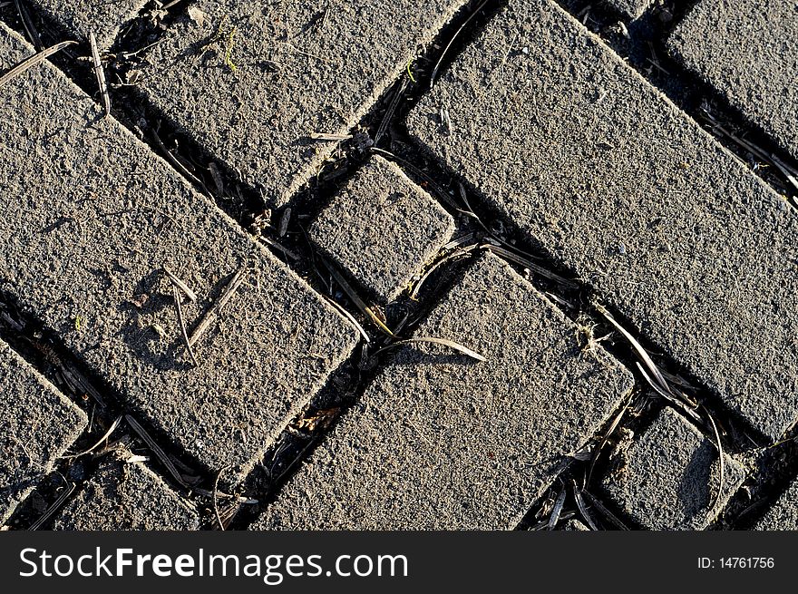 Old Brick pattern in zigzag design with grass growing in between the cracks
