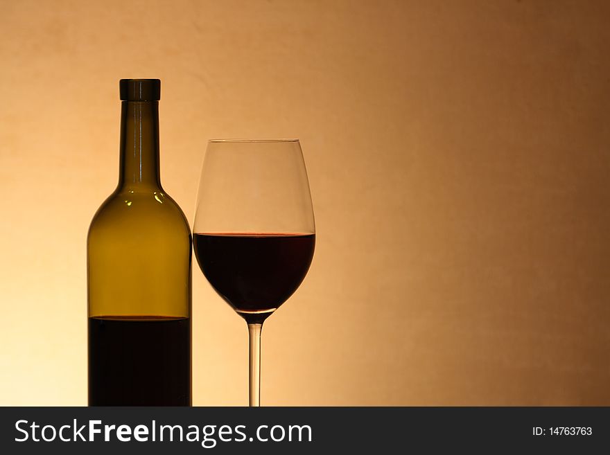 Wineglass near bottle of red wine with reverberation on brown background