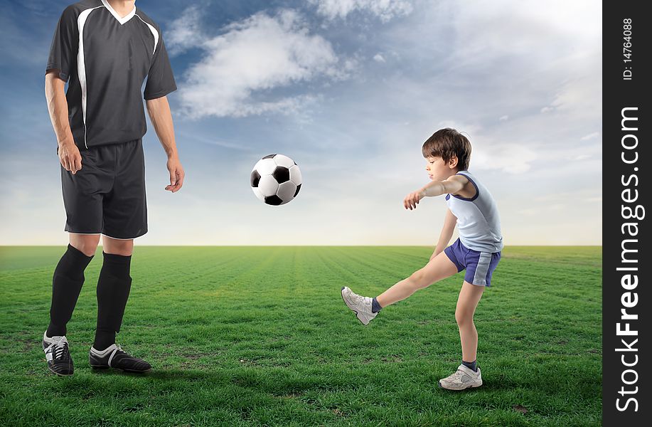 Child kicking a ball and older football player next to him. Child kicking a ball and older football player next to him