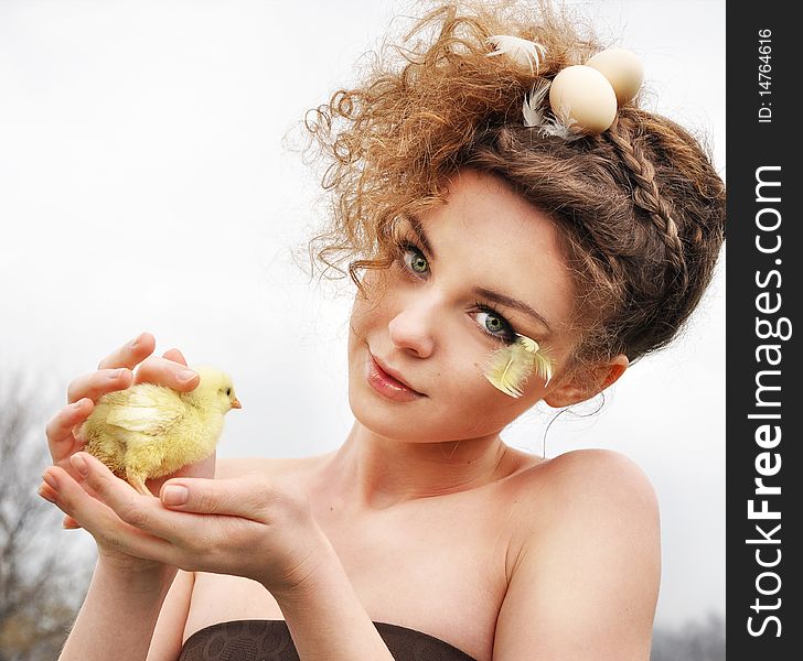 Girl with an original hair-do and little chicken in hands. Girl with an original hair-do and little chicken in hands