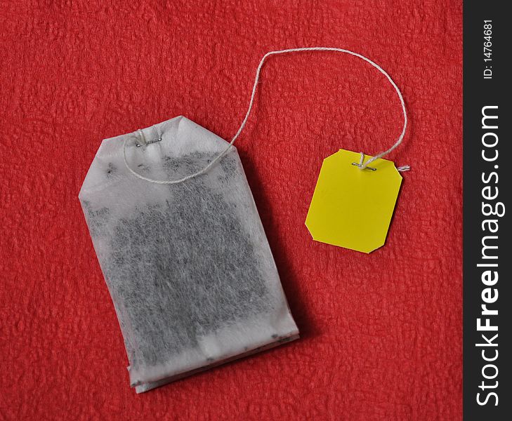 Yellow labeled teabag on red background