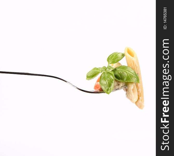 Penne with white vegetable sauce on a fork decorated with basil. Penne with white vegetable sauce on a fork decorated with basil