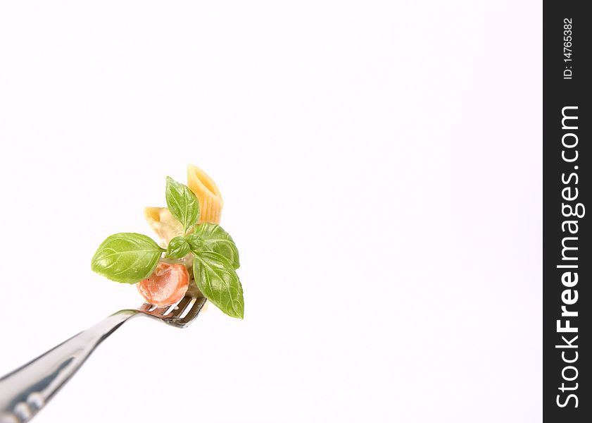 Penne with white vegetable sauce on a fork decorated with basil. Penne with white vegetable sauce on a fork decorated with basil