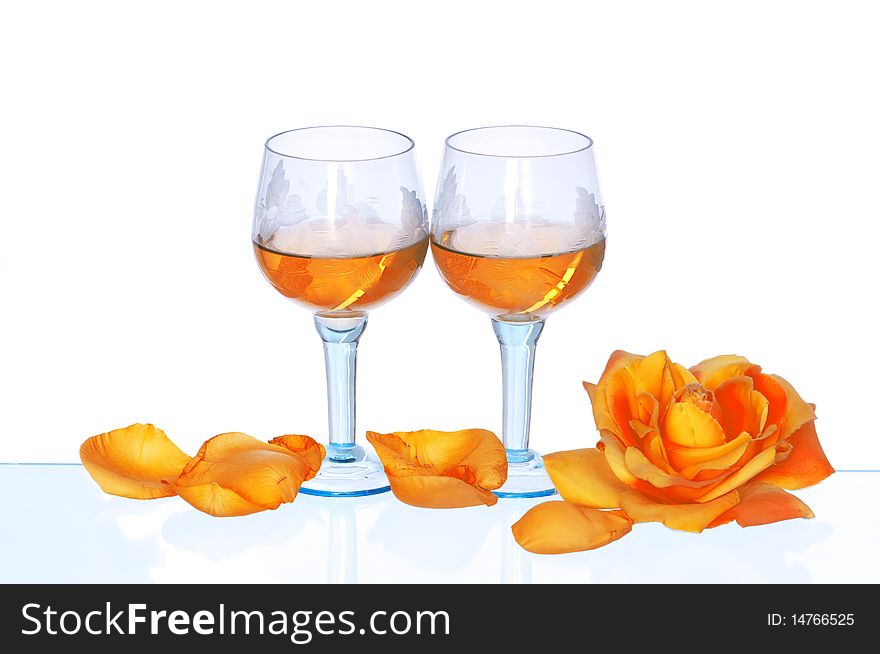 Two tumblers with white wine and yellow rose on the party. Two tumblers with white wine and yellow rose on the party