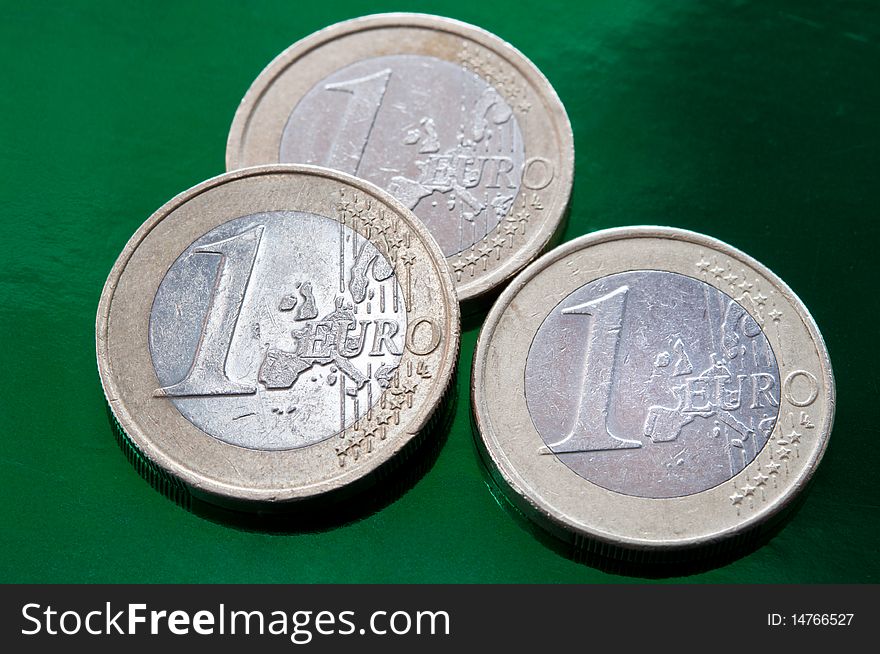 Three euro coins on a green background. closeup.