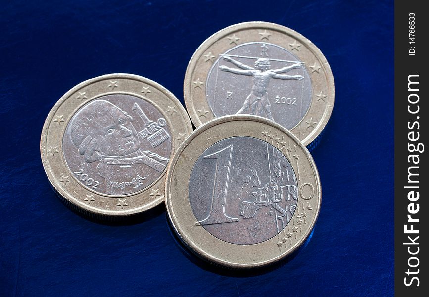 Three euro coins on a blue background. closeup.