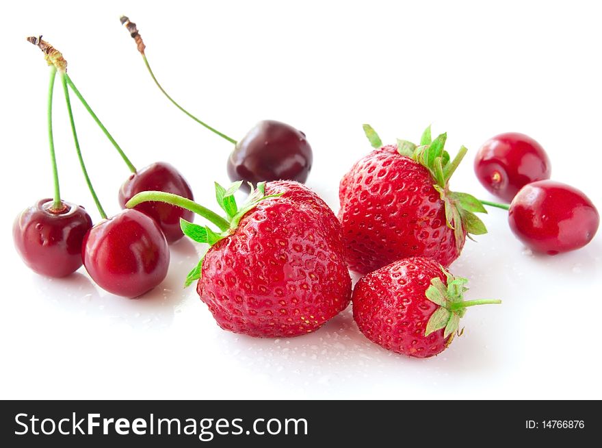 Strawberries and cherries on a white background in droplets of water. Strawberries and cherries on a white background in droplets of water