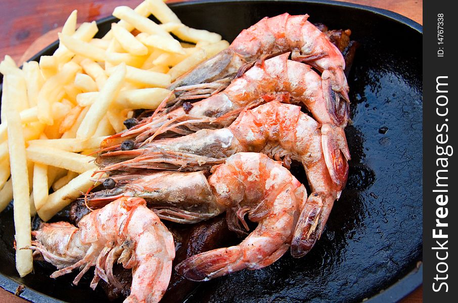 Prepared fried prawns and french fries on cast iron plate. Prepared fried prawns and french fries on cast iron plate
