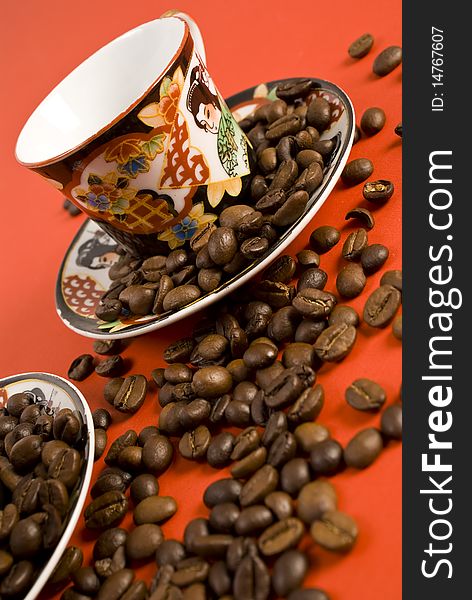 Coffee beans and cup on red background