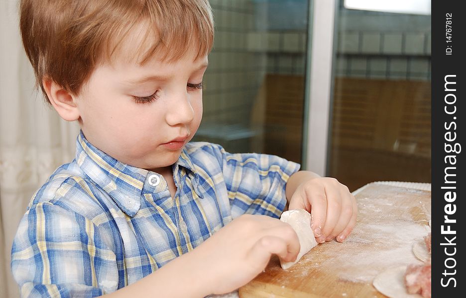 Little boy preparing russian meat dumplings