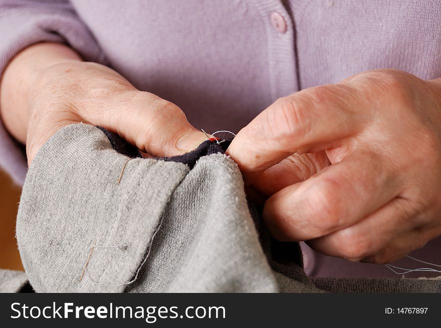 Hands of elderly woman repairing the clothes. Hands of elderly woman repairing the clothes