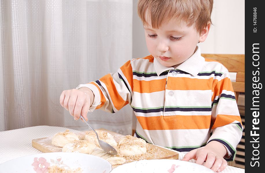 Little boy making buns in his home