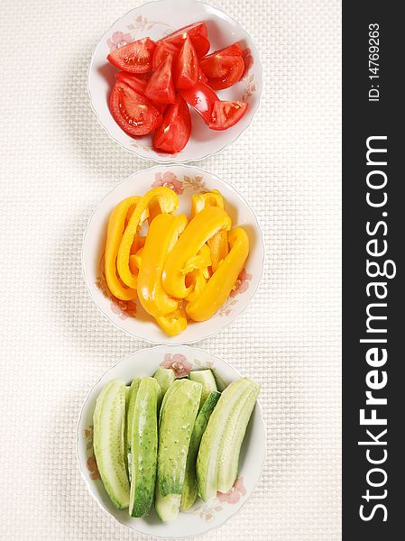 Sliced tomato, cucumber and bell pepper on the plates. Sliced tomato, cucumber and bell pepper on the plates