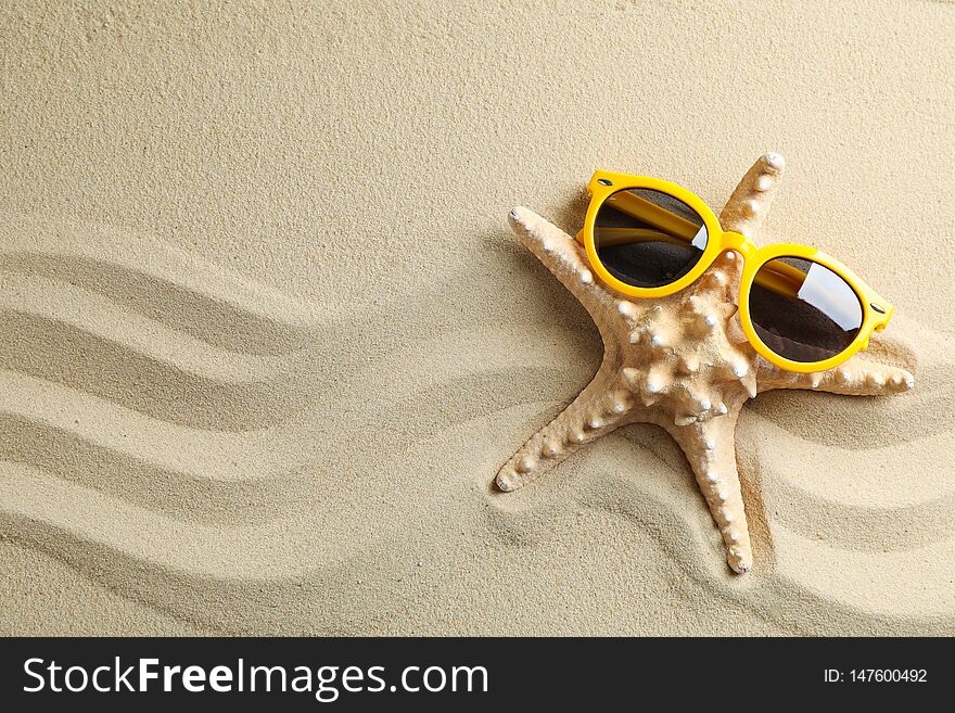 Clear sea sand with starfish and sunglasses, space for text. Summer vacation background