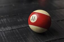 Old Billiard Ball Number 11 Striped White And Red On Black Wooden Table Background, Copy Space Royalty Free Stock Photography