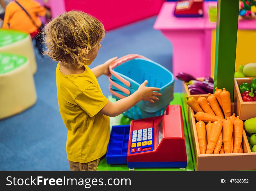 Boy shopping fruits and vegetables in a toy supermarket.