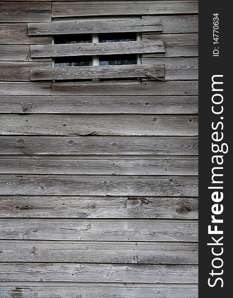 Wooden wall of the old rustic barn with a window. Texture, background. Wooden wall of the old rustic barn with a window. Texture, background