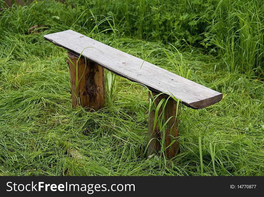 Wooden bench in village among not oblique grass