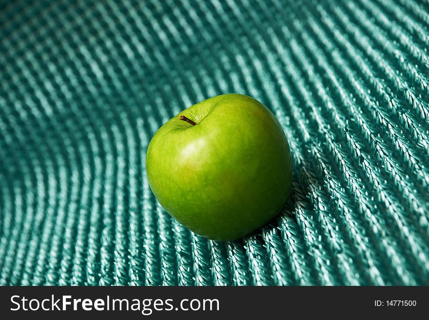 A green apple on blue background