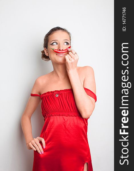 Young girl in red dress with chili pepper on her lips