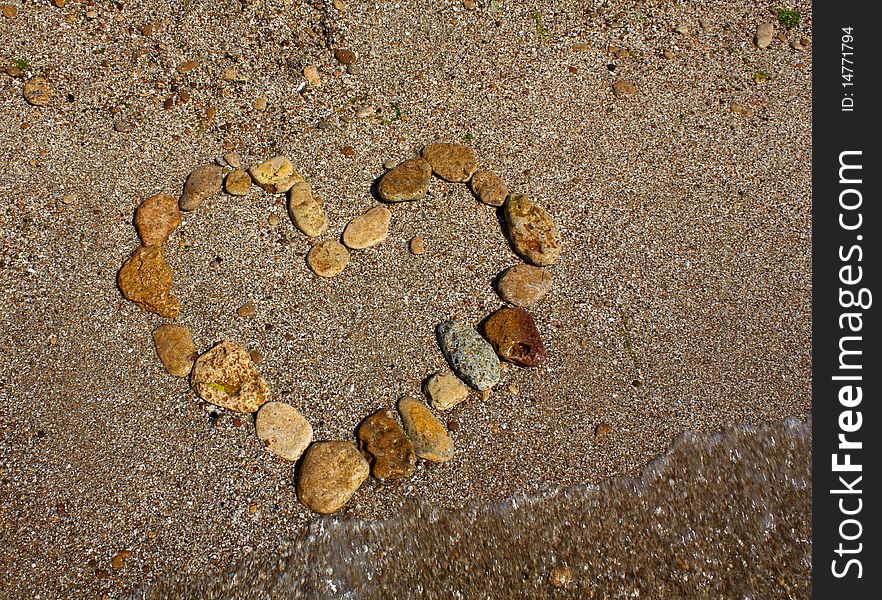 Heart from stones on sand seacoast