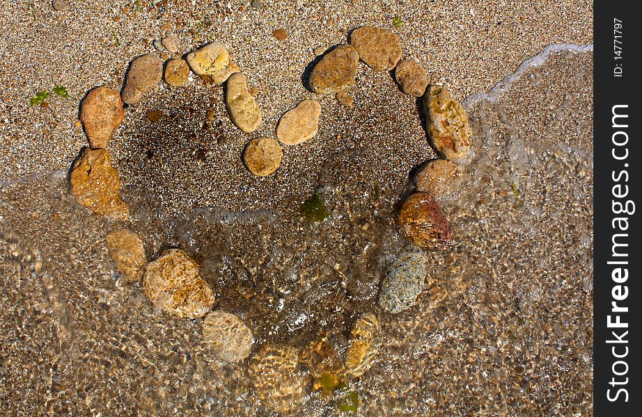 Heart from stones on sand seacoast