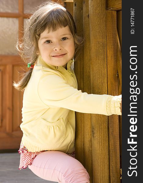 The beautiful lovely girl with long dark hair in a yellow jacket embraces a fence. The beautiful lovely girl with long dark hair in a yellow jacket embraces a fence