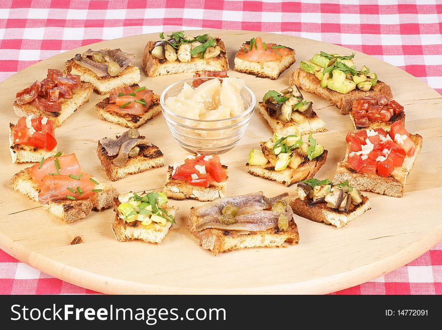 Typical italian appetizer: parmigiano reggiano and bruschetta (grilled bread rubbed with garlic and topped with various ingredients). Studio shot. Typical italian appetizer: parmigiano reggiano and bruschetta (grilled bread rubbed with garlic and topped with various ingredients). Studio shot.