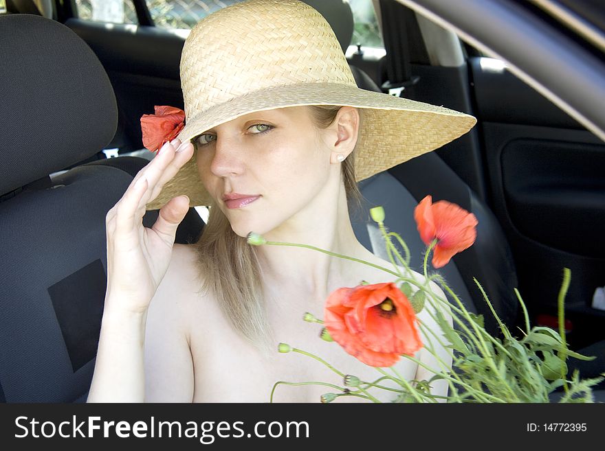 The woman in a hat with red poppies sits in the car. The woman in a hat with red poppies sits in the car