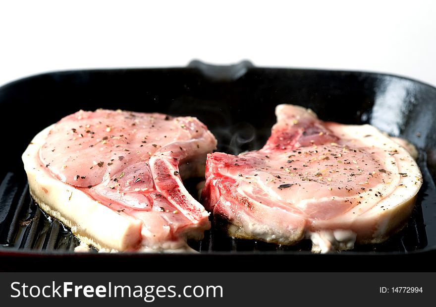 Close up of a pork chop cooking on a griddle pan. Close up of a pork chop cooking on a griddle pan